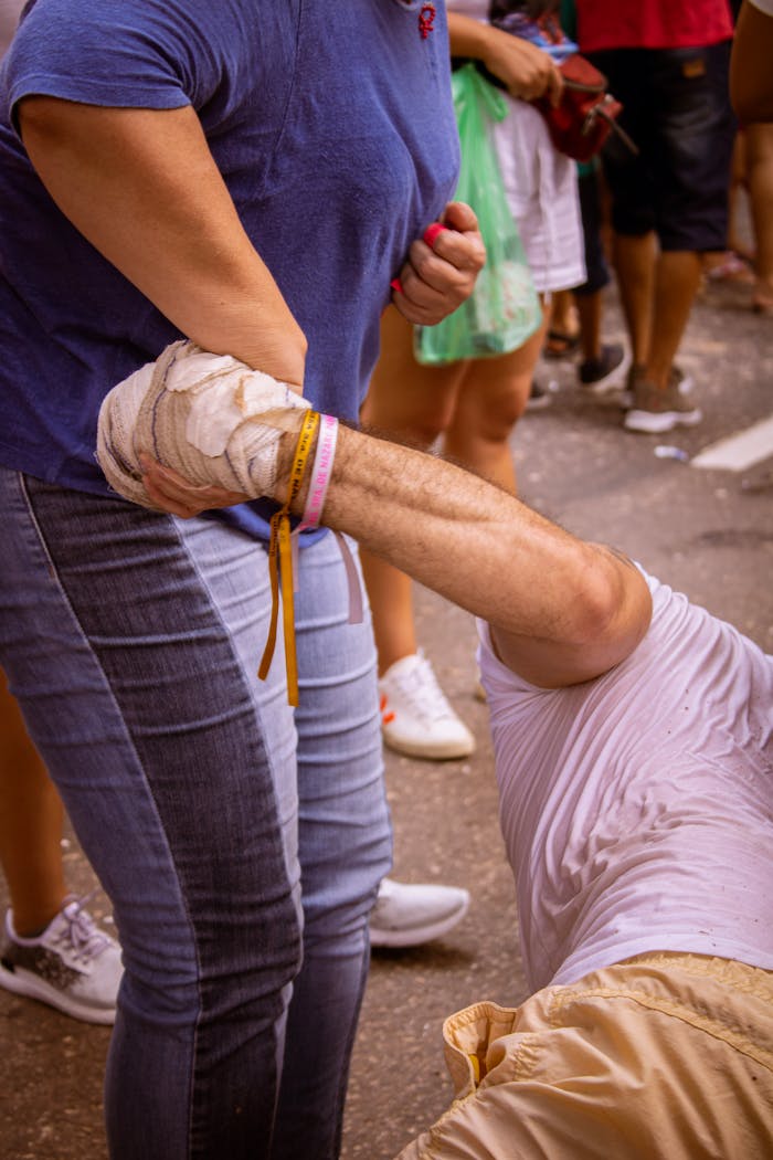 An injured person receives assistance during a street protest in a city.