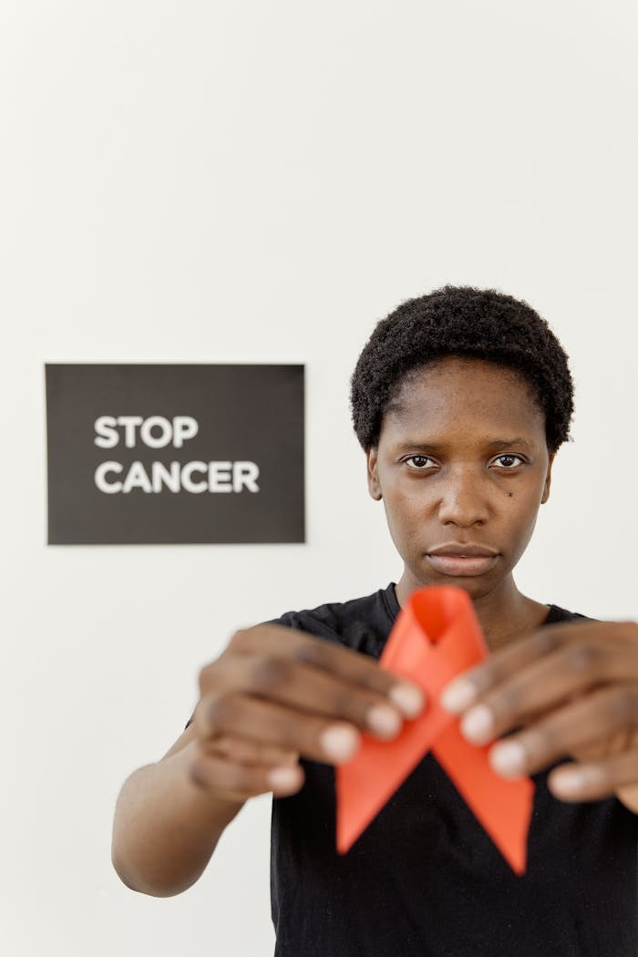 Empowering portrait of a woman holding a red ribbon for Stop Cancer awareness.